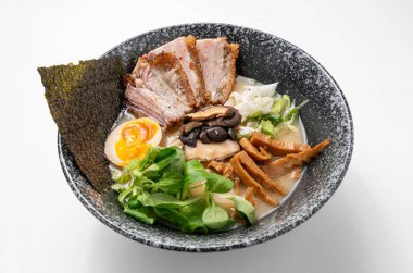 Erişteli Miso Ramen, domuz göbeği, yosun, yeşillik, mantar, yumurta ve yeşil soğan beyaz arka planda kırsal siyah bir kasede. Canlı, geleneksel bir Asya yemeği. Çin ve Japon mutfağı sergileniyor..
