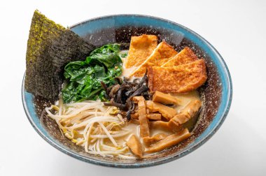 Erişteli vejetaryen miso ramen, yosun, ıspanak, mantar, fasulye filizi ve beyaz arka planda mavi bir kasede tofu. Canlı, geleneksel bir Asya yemeği. Çin ve Japon mutfağı sergileniyor.