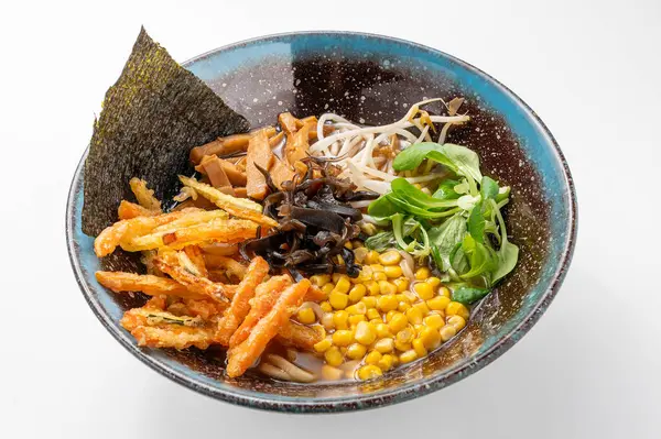 Şehriyeli vejetaryen shoyu ramen, yosun, mısır, yeşillik, mantar ve beyaz arka planda kırsal mavi bir kasede tempura. Canlı, geleneksel bir Asya yemeği Çin ve Japon mutfak stillerini sergiliyor..