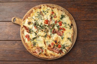 İtalyan Maxi pizza, mozzarella, çiğ jambon, roket, vişneli domates, fontina peyniri ve mantar yağı, koyu ahşap arka planda izole edilmiş. Canlı, gurme bir fotoğraf, İtalyan mutfağı temaları için mükemmel.