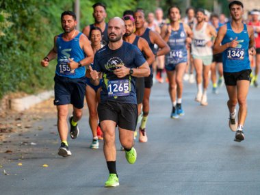 Sporcular yarı maratonda yarıya yarışıyorlar. Amatör koşucular, şehir merkezinde sağlıklı yaşam tarzı ve spor temaları için azim ve enerji gösterisi yapıyorlar. Foligno, İtalya, 20 Haziran 2025