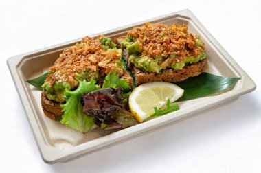 Ezilmiş avokado, miso macunu, susam tohumu, baharatlı yağ, soğan ve limon aromalı kızarmış ekmek, beyaz arka planda izole edilmiş. Doğal ışık, sokak yemekleri mutfağında popüler olan bu sağlıklı vejetaryen atıştırmalığını geliştirir..