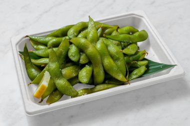 Beyaz arka planda hazır yemek konteynırında taze edamame. Doğal ışık bu sağlıklı Japon yemeğini geliştirir, Asyalı füzyon aşıkları için mükemmeldir.