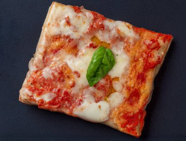 Domates soslu İtalyan Margherita pizza dilimi, mozzarella ve taze fesleğen, yukarıdan siyah arka planda çekilmiş. Yatay, doğal ışık, canlı renkler, otantik İtalyan aromaları sergileniyor..