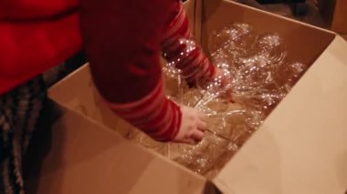 Bir fabrika işçisi boyamadan önce Noel süslemelerini bir kutuya koyar. Noel süslemeleri üretimi. Bardak boş Noel topları. Noel tatili. Yüksek kalite 4k görüntü