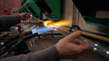 Bir kadın işçi, yüksek sıcaklıkta camları eriterek gaz alevi üzerine şenlikli bir Noel süsü oluşturuyor. Yüksek kalite 4k görüntü