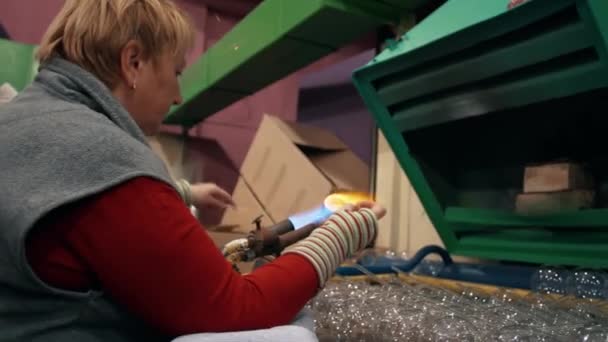 一个女工用燃烧器吹圣诞玩具而加热玻璃杯的侧视图 玻璃新年玩具的制造 玻璃鼓风机 高质量的4K镜头 — 图库视频影像