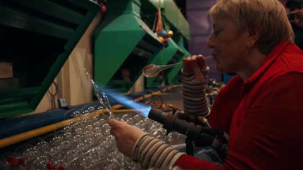 Kobieta Pracownik Zdmuchuje Świąteczną Szklaną Zabawkę Ogrzewając Szklankę Palnikiem Pożarowym — Wideo stockowe