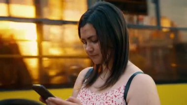 Akıllı telefonda anlık mesajlar kullanan genç bir kız, şehir sokaklarında dikilirken arkadaşlarıyla iletişim kurar. Mesajlar, modern teknolojiler, sohbet, internet iletişimi. Yüksek kaliteli 4K görüntü.