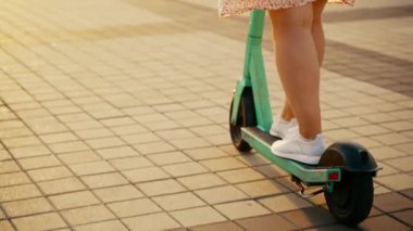 Güneşin altında şehirde scooterla gezen bir kızın arkasından manzara. Yüksek kalite 4k görüntü