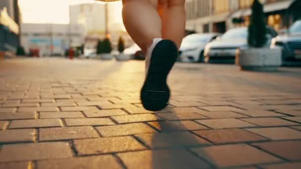 穿着时髦的白色运动鞋沿着城市街道行走的女性腿的特写 这个女孩沿着城里街上的人行道走着 自然的阳光 高质量的4K镜头 — 图库视频影像