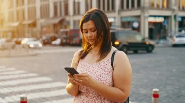 Kız, sosyal ağlar için akıllı telefon kullanıyor. Şehrin caddesinde dikilip gelen mesajdan gülümsüyor. Modern teknolojiler. İnternet iletişimi. Yüksek kalite 4k görüntü