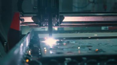 Modern bir metal levha lazer kesme makinesinin yakın çekimi. Modern bir CNC fiber lazer makinesi metal levha üzerindeki desenleri keser. Kesme işlemi sırasında lazer ışınından parlak kıvılcımlar uçuşuyor. 4k
