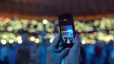 Gençler konserde telefonla video kaydediyor, yakın çekim seyirciler, hayranlar ellerini kaldırıyor, canlı müzikten, festival etkinliğinden zevk alıyorlar. Yüksek kalite 4k görüntü