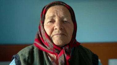 Yeşil gözlü başörtüsü takmış yaşlı bir büyükannenin portresi. Yüzünde kırışıklıklar olan yaşlı bir yüz. Yaşlı bir kadının buruşuk suratının yakın çekimi. Yüksek kalite 4k görüntü