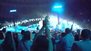 Konserde dans eden bir kızın elleri dans hayranlarının ve sahnenin arka planında değildir. Konser kalabalığının siluetleri. Konserdeki mutlu insanlar. Yüksek kalite 4k görüntü