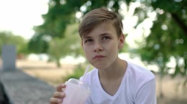 Milk shake içen yakışıklı beyaz bir çocuğun yakın çekimi. Adam yiyip içiyor. Yemeğin zevki. Modern hayat. Ön planda. 4k biçiminde yüksek kaliteli atış