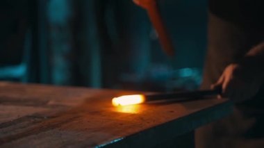 Sıcak metal darbelerine yakın çekim. Demirci bir elinde iş parçasını tutar, diğer elinde de ürünü ürettiği çekiç. Yüksek kalite 4k görüntü