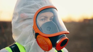 Bir insan COVID-19 enfeksiyonunu önlemek için sokakta solunum cihazıyla ve koruyucu elbiseyle dikiliyor. Virüs salgınıyla savaşmak. Koronavirüs salgını. 4k biçiminde yüksek kaliteli atış