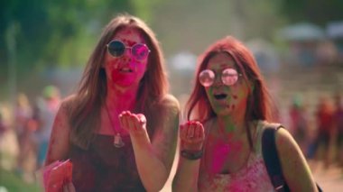 Holi Renk Festivali 'nde neşeli kızlar kutlama yapıyor. Kızlar eğleniyor ve kameraya doğru boyalarını üflüyorlar. Eğlenceliydi. Rahatlama. Kutlama. Kutlama. Holi renk festivali. Yüksek kalite 4K görüntü.