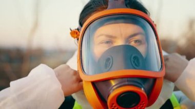 A person stands outdoors in a respirator, wears a protective suit in order to avoid infection with COVID-19. Fighting a virus outbreak. Coronavirus pandemic. High quality 4k footage