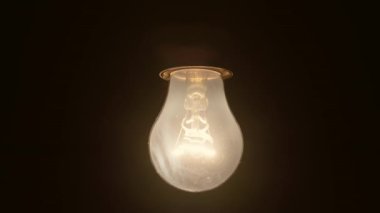 Slow motion of turning off an incandescent light bulb on a dark background. The light bulb lit up and slowly went out. High quality 4k footage