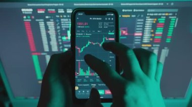 Broker viewing cryptocurrency candlestick chart on black screen in dark room.Male touches smartphone screen with finger.Chart of growth, fall of bitcoin.Dynamics, statistics, stock exchange data.4k
