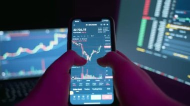 A people sits at home with a laptop and phone, watching cryptocurrency trading. Exchange, rise and fall graph, financial business concept. Trader, exchange, online. High quality 4k footage