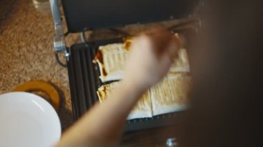 Açık ızgaranın en üst görüntüsü ve hazır shawarma. Tabak, spatula yardımıyla bir tabağa konur. Shawarma elektrikli ızgaraya yakın çekim yapıyor. Yüksek kalite 4k görüntü