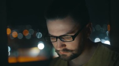 Sosyal ağda mesajlaşan bir adamın portresi, Bokeh 'teki şehir ışıklarının arka planına karşı telefona odaklanmış. Mobil cihaz kullanılıyor. Yüksek kalite 4K görüntü.