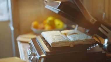 Bir kadın mutfak masasında lavash shawarma pişiren bir elektrikli ızgara açıyor. Yan görüş. Pita 'lı ev yapımı shawarma hazır olsun. Yüksek kalite 4k görüntü