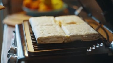 Bir kadın mutfak masasında lavash shawarma pişiren bir elektrikli ızgara açıyor. Yan görüş. Pita 'lı ev yapımı shawarma hazır olsun. Yüksek kalite 4k görüntü