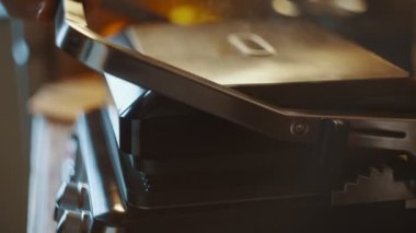 Bir kadın mutfak masasında lavash shawarma pişiren bir elektrikli ızgara açıyor. Yan görüş. Pita 'lı ev yapımı shawarma hazır olsun. Yüksek kalite 4k görüntü