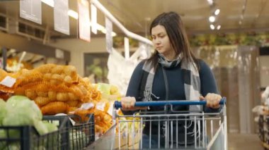 Bir kadın süpermarketin camına doğru yürür ve çekmeceden yeşil lahana seçer. Bir kadın süpermarkette alışveriş yapıyor. 4k biçiminde yüksek kaliteli atış