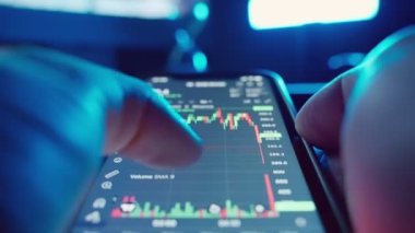 Cryptocurrency stock market on mobile phone screen.bA people sits at home with a laptop and phone, watching cryptocurrency trading.Stock market chart of Bitcoin currency. High quality 4k footage