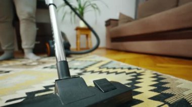 Ön manzara: modern bir elektrikli süpürge ile oturma odasını temizlemek, aşağıdan düşük açı. Teknoloji, ev işi, rutin ve ev idaresi konsepti. Yüksek kalite 4k görüntü