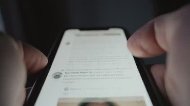 Telefonun ekranındaki haber kaynağı, parmaklarını dokunmatik ekranda gezdiren ve sosyal ağlarda yayını kaydıran bir adamın elinde. Kalite 4k çerçeve