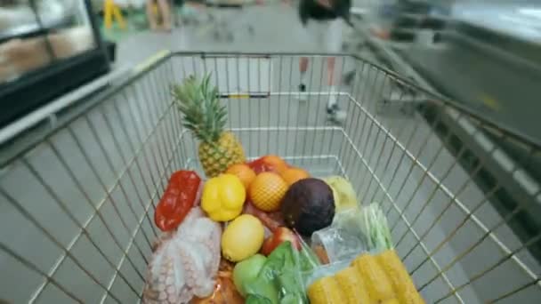 超市里用各种食品填满购物车的时间 在大型超级市场的不同过道之间轮流摆放各种有用的产品 — 图库视频影像