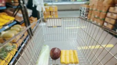 Bir süpermarket tramvayı marketteki sıraların arasından geçer ve yiyecek, meyve, sebze ve etle doludur. Zaman ayarlı. Hiperlapse. İnsanlar süpermarketten alışveriş yapıyor. Yüksek kalite 4k görüntü