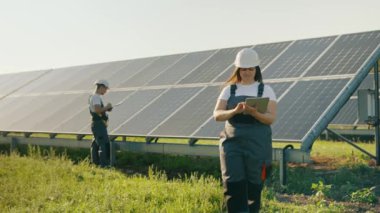 Alternatif elektrik üretiminde çalışan işçiler veri toplayıp analiz ediyorlar. Güneş panelleri, yeşil enerji kullanan enerji üretimi. Bir alana yerleştirilmiş bir ekolojik enerji santralinin güneş panelleri.