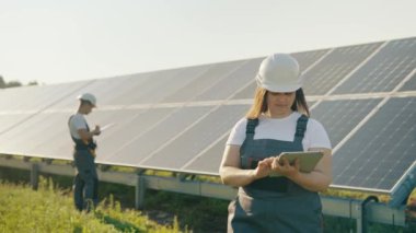 Bir kadın mühendis güneş panelleri hakkında etkili bilgiler toplamak için bir tasarım tableti kullanır. Fotovoltaik güneş çiftliği. Yeşil enerji. Çarşamba.