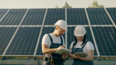 Bir kadın mühendis güneş panelleri hakkında etkili bilgiler toplamak için bir tasarım tableti kullanır. Fotovoltaik güneş çiftliği. Yeşil enerji. Çarşamba.