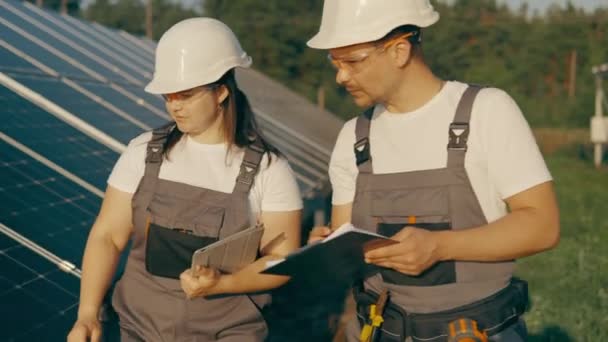 太阳能公园 生态工程学 两名快乐的男性和女性机械工人在农田里行走 探索太阳能电池的安装 合作小组 高质量的4K镜头 — 图库视频影像