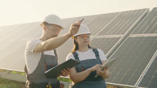 代替電力の生産でオーバーオールの労働者は データを収集し分析します 太陽光パネルを使用してエネルギー生産 グリーンエネルギー フィールドに配置された生態系発電所の太陽光発電パネル — ストック動画
