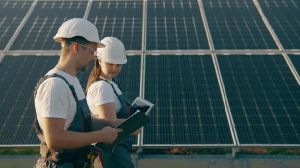 チーフエンジニアと専門家は 農場を歩きながら太陽光発電所の結果に関する報告書を研究しています ビジネスチーム クリーンエネルギー インダストリー 高品質4Kシューティング — ストック動画