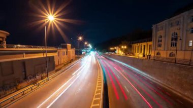Gece şehrinin caddesinde yoğun bir akşam trafiği var. Hızlı hareket eden arabaların bulanık ışıklarıyla zaman aşımı. Gece trafik ışıkları ve fenerlere odaklanmış bokeh görünümü. Yüksek kalite 4k video