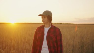 Tabletli bir kadın çiftçi buğday tarlasında çalışıyor, hasat sürecini kontrol ediyor. Kız bir tablet kullanıyor ve hasat etmeyi planlıyor. Tarım teknolojisi kavramı. Yüksek kalite 4K görüntü