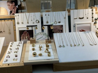 Varşova, Polonya - 28 Nisan 2025: Modern bir perakende satış ortamında kolyeler, yüzükler ve küpelerle sergilenen şık altın mücevher koleksiyonu