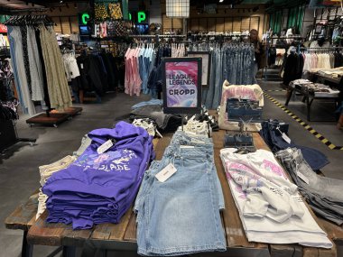 Varşova, Polonya - 28 Nisan 2025: Mor kapüşonlu ve kot pantolonları modern bir perakende ortamda sergilenen ticari eşyalar