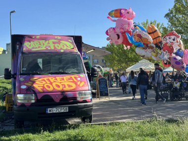 Varşova, Polonya - 04 Mayıs 2025: Canlı sokak yemek kamyonu açık hava pazarına park edilmiş graffiti ile gıda ve festival atmosferinin keyfini çıkaran insanlarla dolu